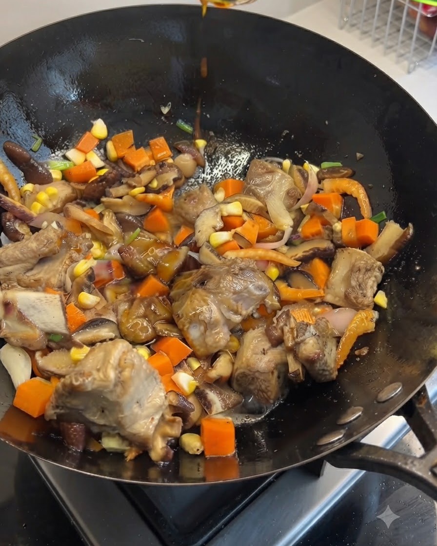 Salse di soia scura e chiara versate dallalto in un wok pieno di costine di maiale saltate, carote, funghi e mais.