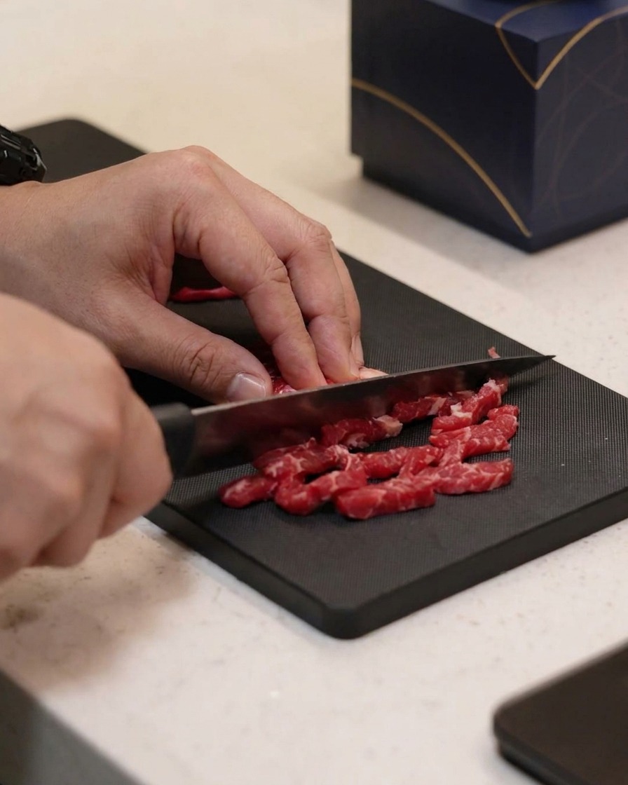 Piccole strisce di manzo condite con olio, sale e pepe su un tagliere.