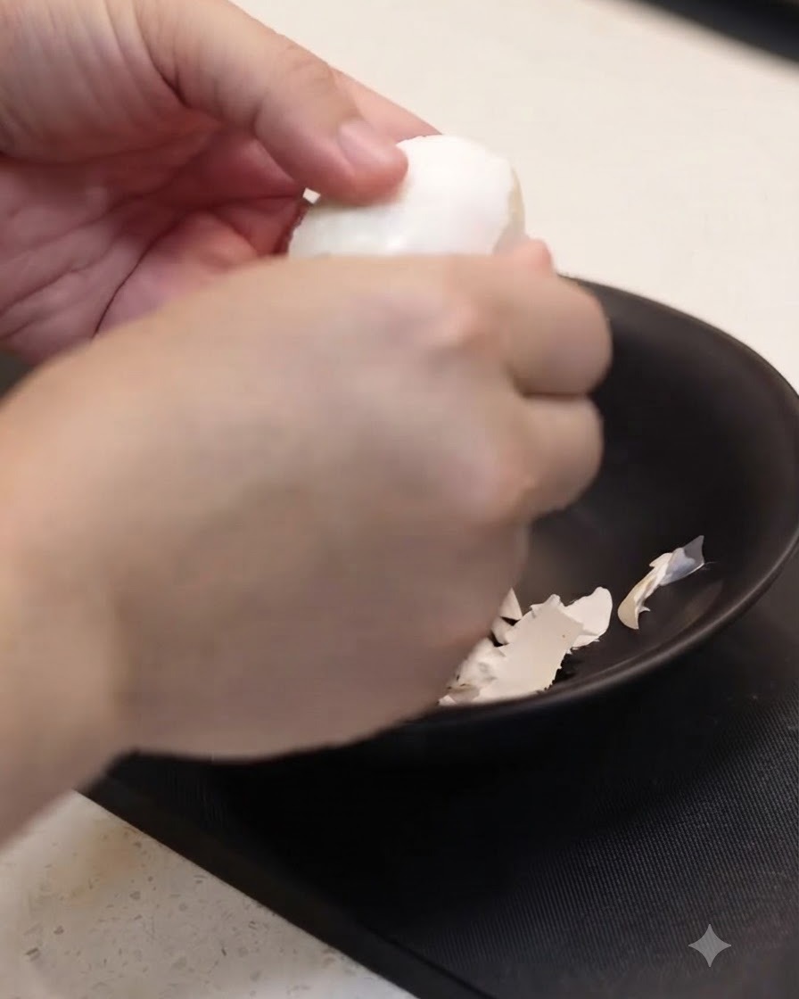 Un uovo cotto accuratamente sbucciato a mano sopra una ciotola nera.