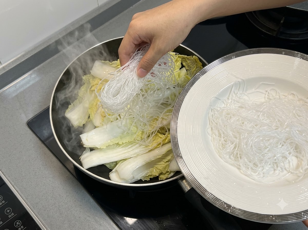 Noodles vermicelli posizionati sopra il cavolo cinese allinterno della padella.