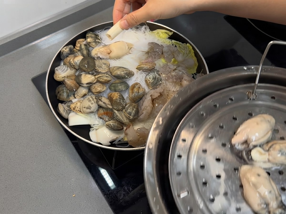 Gamberi e ostriche fresche posizionati sopra la miscela di frutti di mare e noodles nella padella.