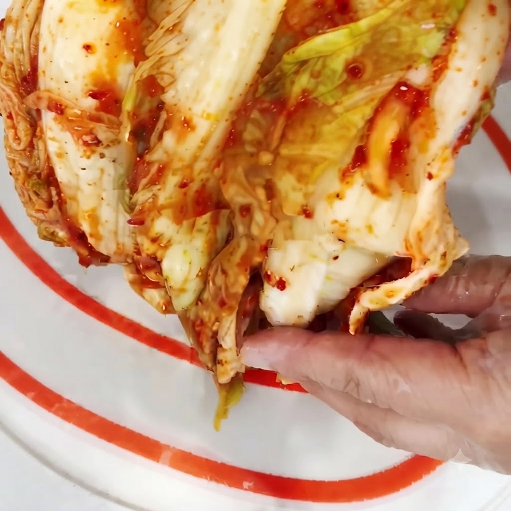 Metà testa di kimchi tagliata a pezzi più piccoli su un tagliere.