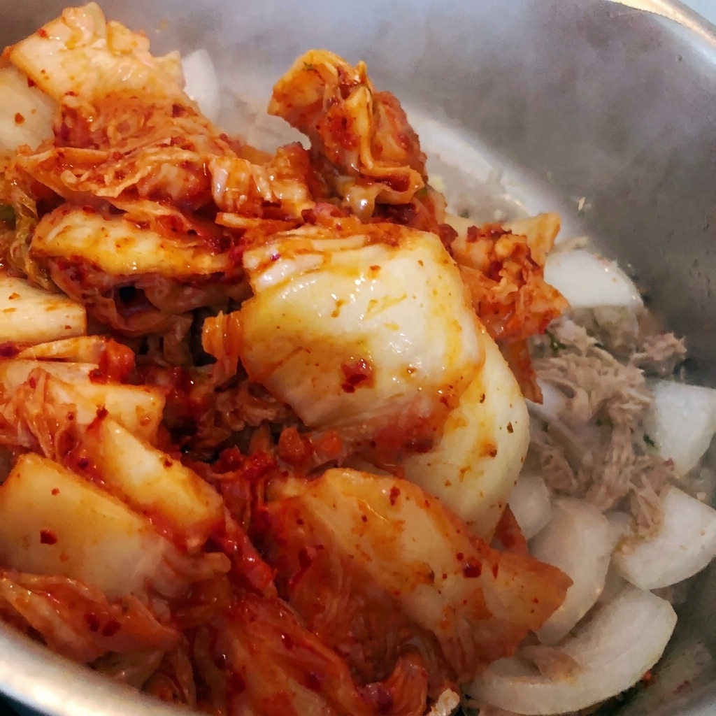 Kimchi tritato gettato nella pentola con gli ingredienti esistenti.