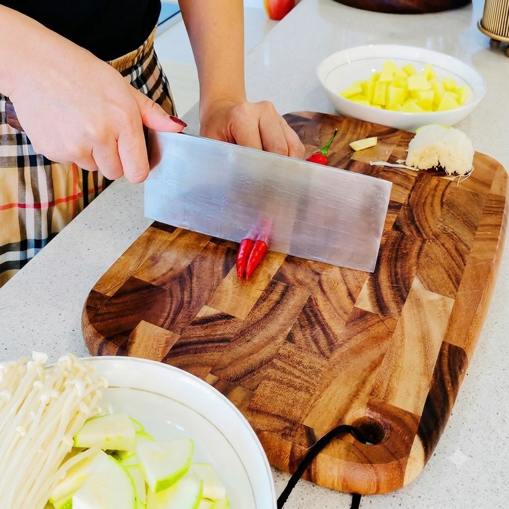 Piccoli peperoncini rossi tritati in pezzi fini su un tagliere di legno.