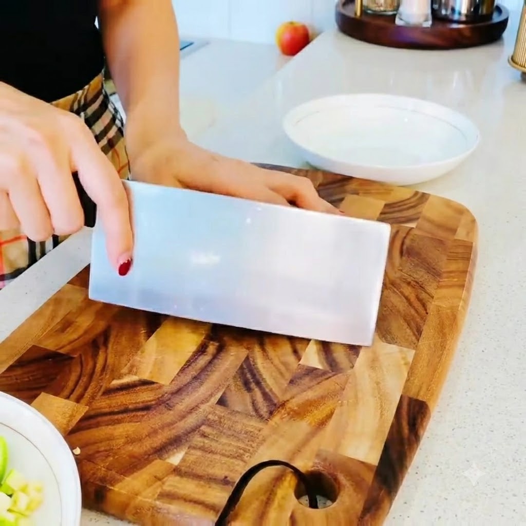 Un mazzetto di funghi enoki con le estremità delle radici tagliate pulite su un tagliere di legno.