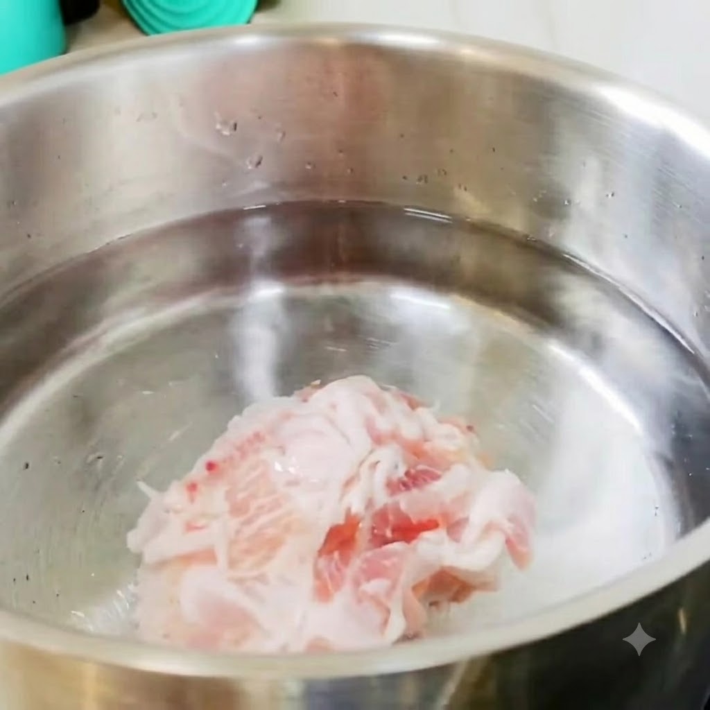 Fette di pancetta di maiale e pezzi di patate in una pentola di acciaio inossidabile con acqua fredda sul fuoco.