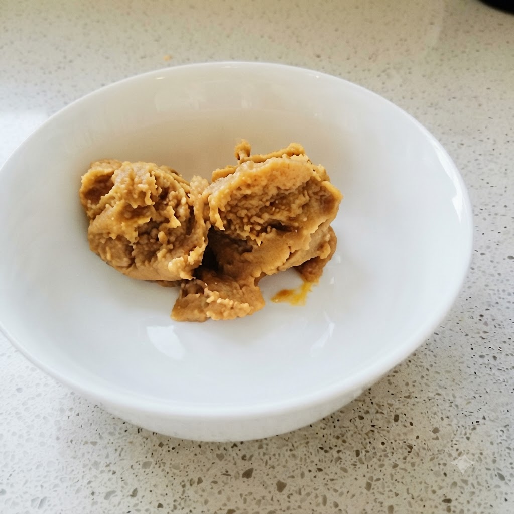 Pasta di soia coreana e pasta di peperoncino mescolate accuratamente in una ciotola bianca con un cucchiaio dorato.