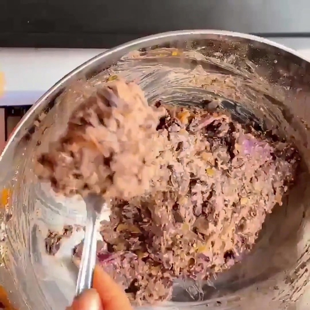 Primo piano di mani che premono e modellano limpasto di fagioli neri in un burger rotondo.