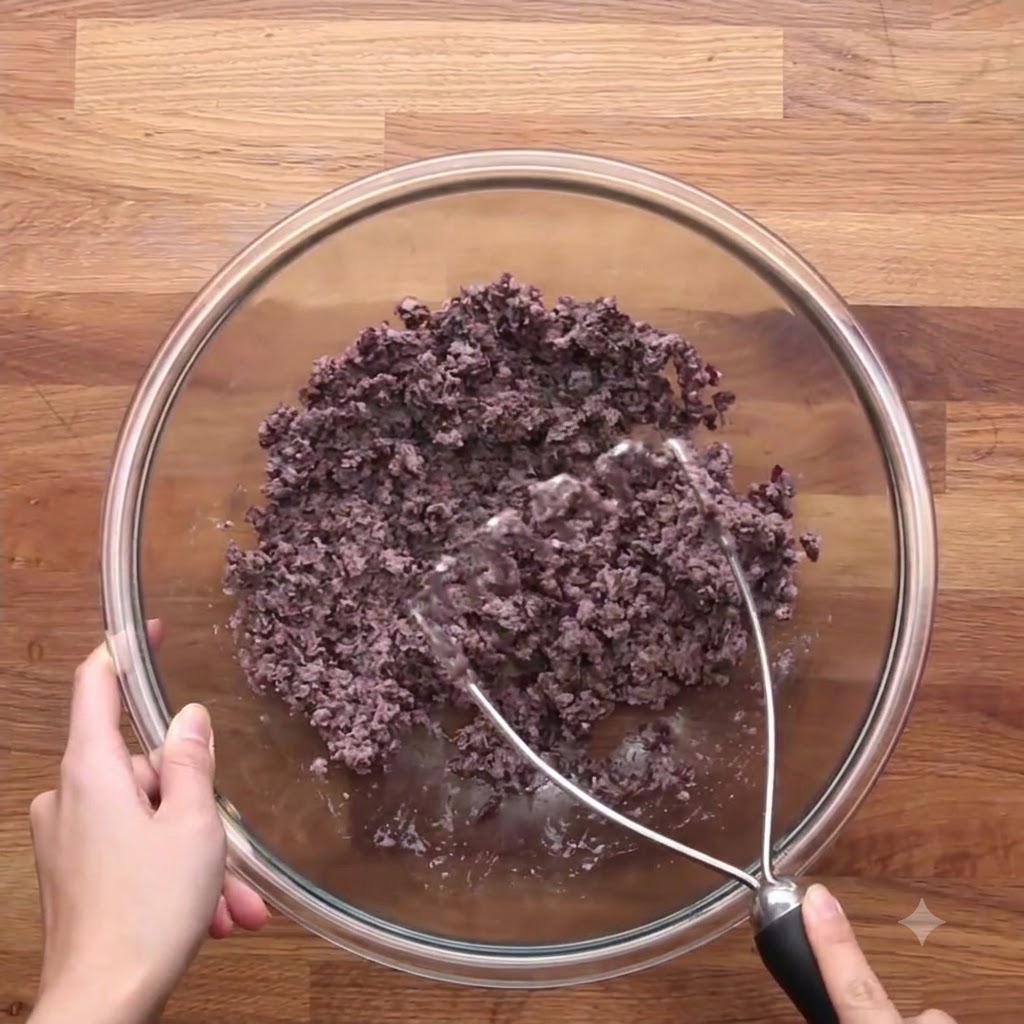 Il composto di cipolle e carote cotte combinato con i fagioli neri schiacciati in una ciotola di vetro.