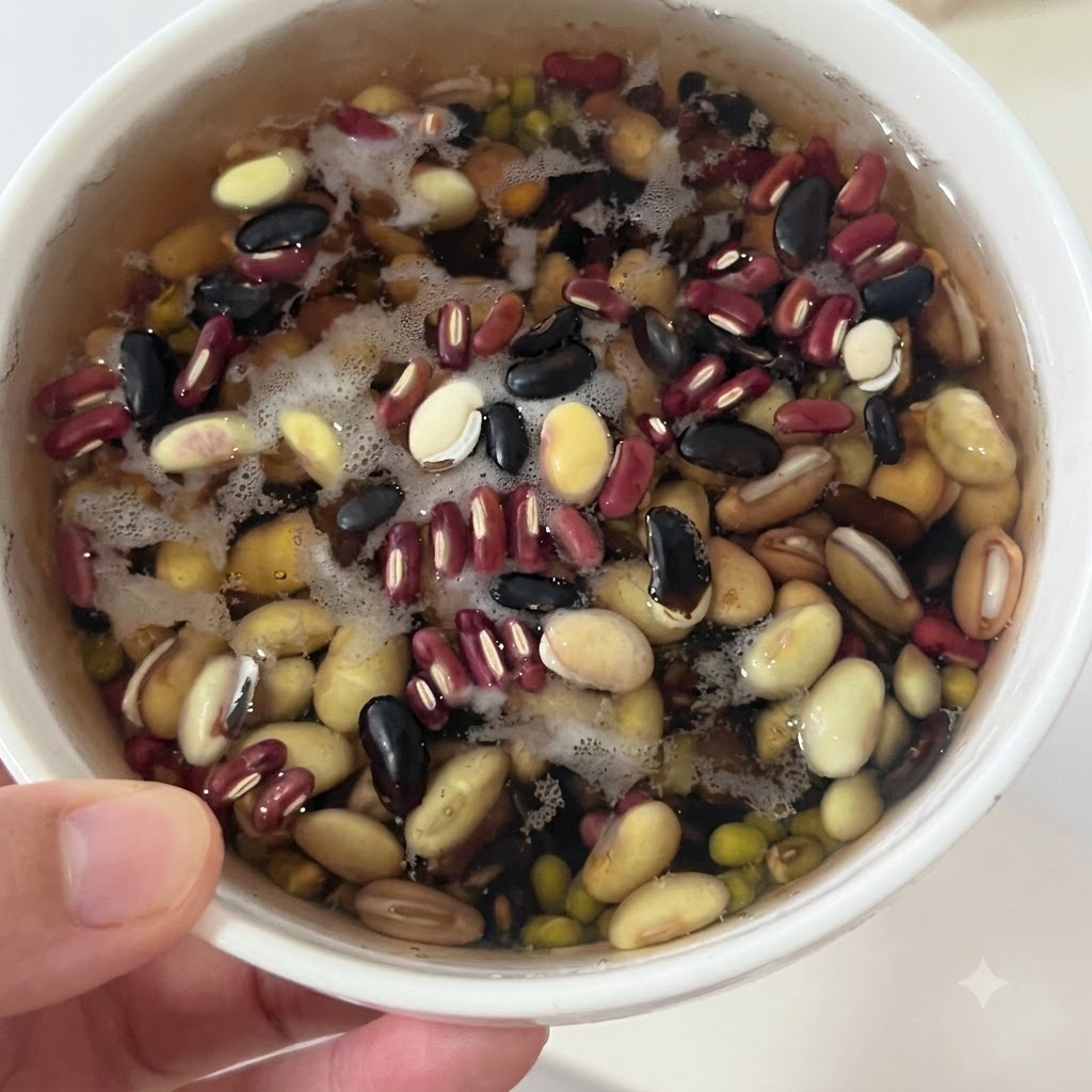 Fagioli misti in ammollo adagiati in una ciotola bianca con acqua prima di essere filtrati.