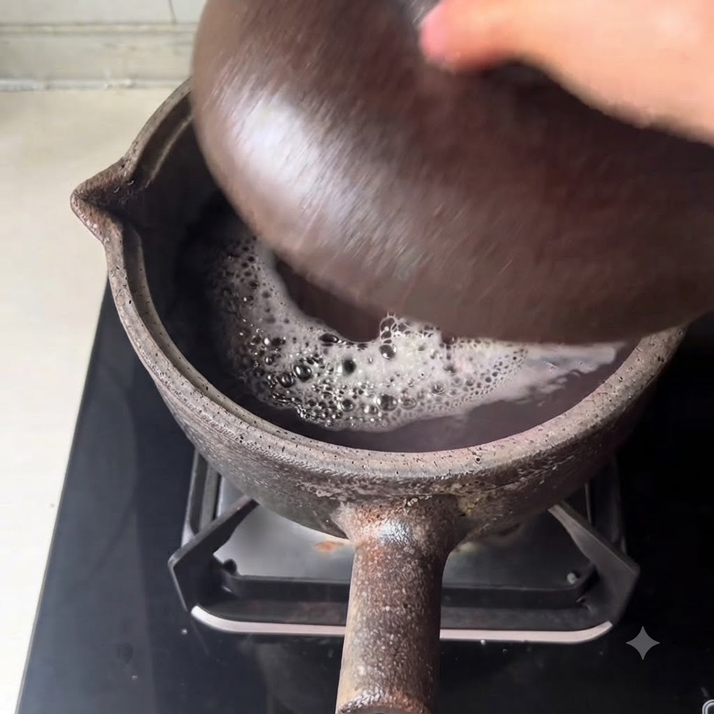 Una vista ravvicinata del brodo scuro che sobbolle e dei fagioli che fanno le bolle allinterno della pentola di terracotta.