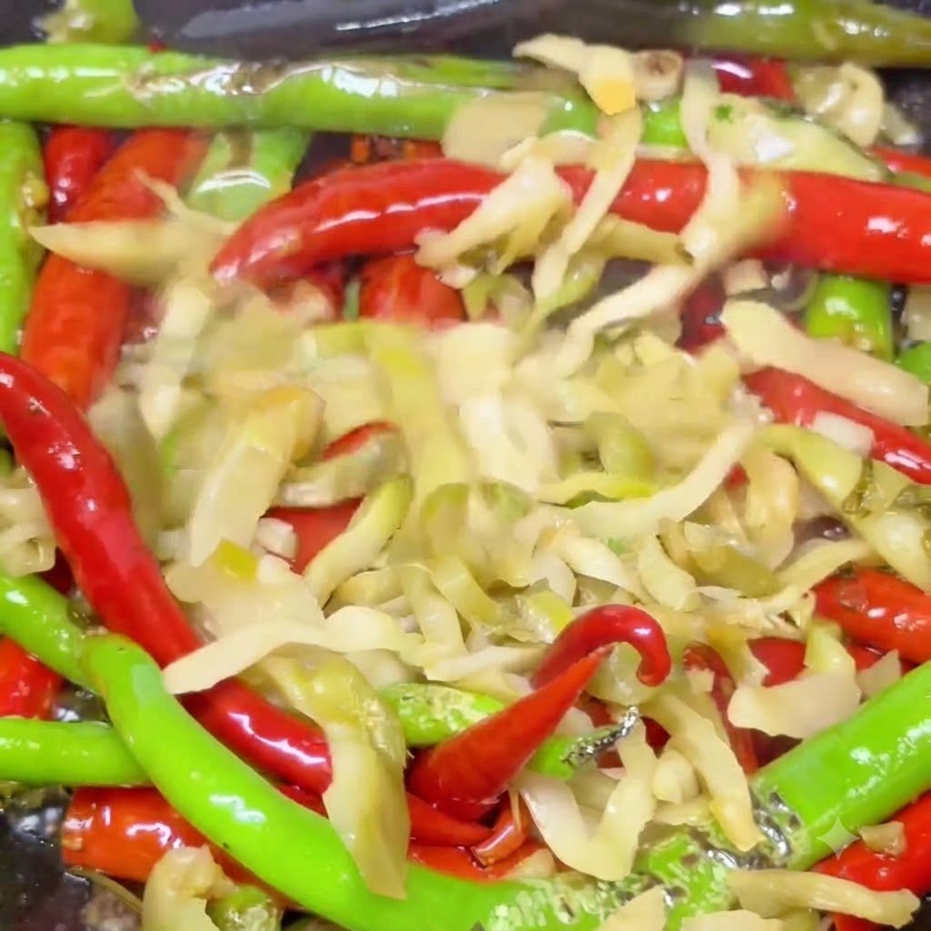 Senape in agrodaglie mescolata con peperoncini rossi e verdi vescicati mentre saltano in un wok caldo.