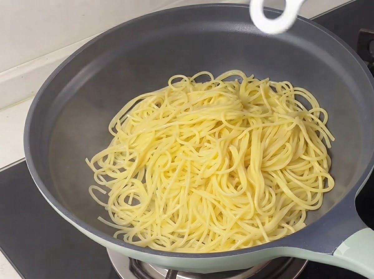 Spaghetti gialli cotti accumulati allinterno di una padella.