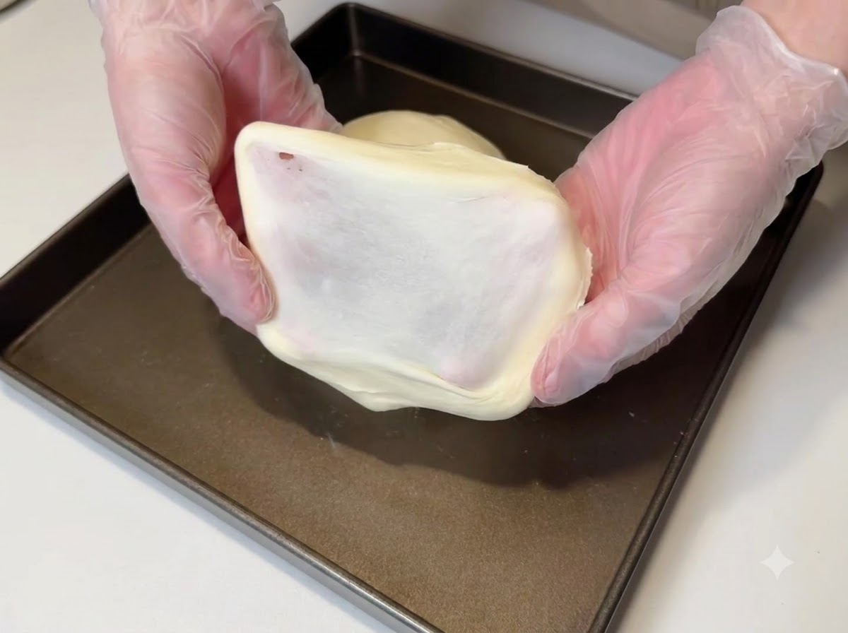 Un pezzo di impasto tirato per mostrare una pellicola spessa e liscia.