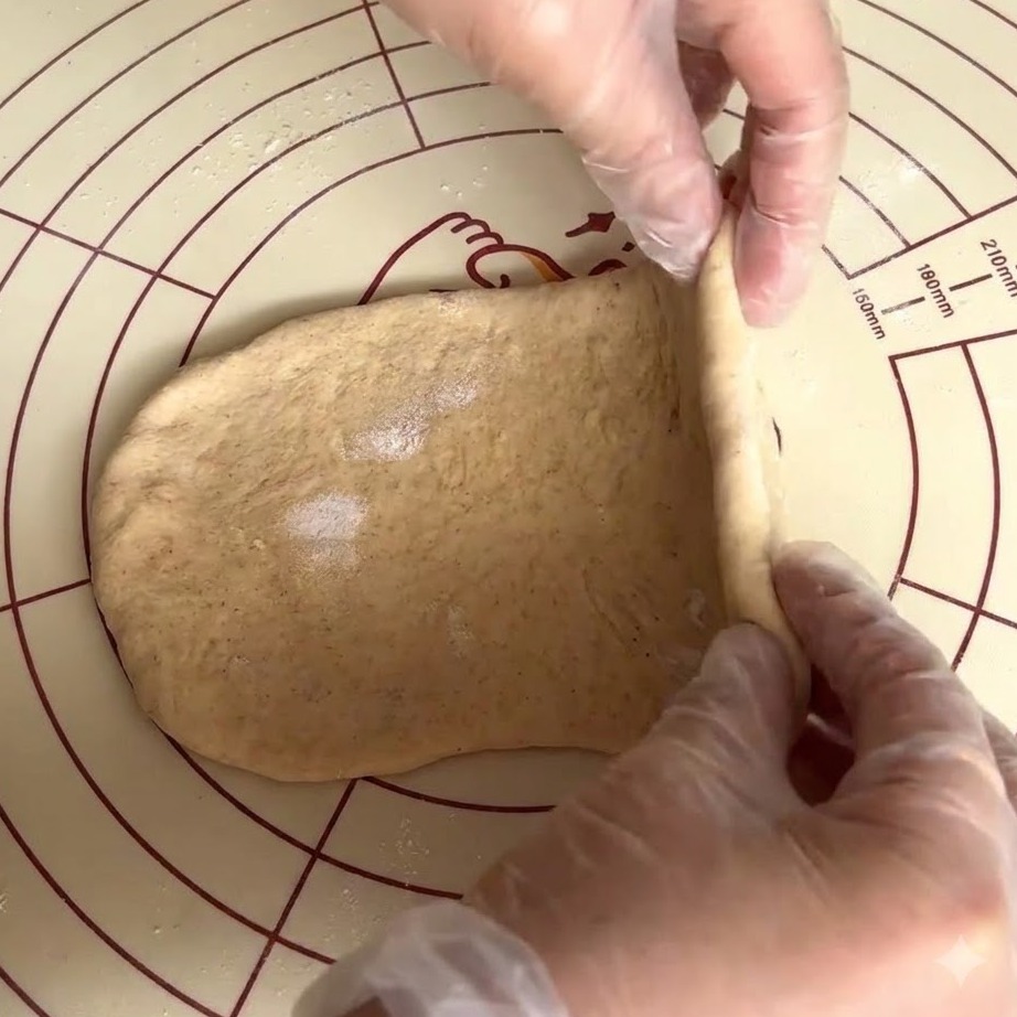 Mani guantate che piegano e pizzicano limpasto integrale appiattito come una trapunta.