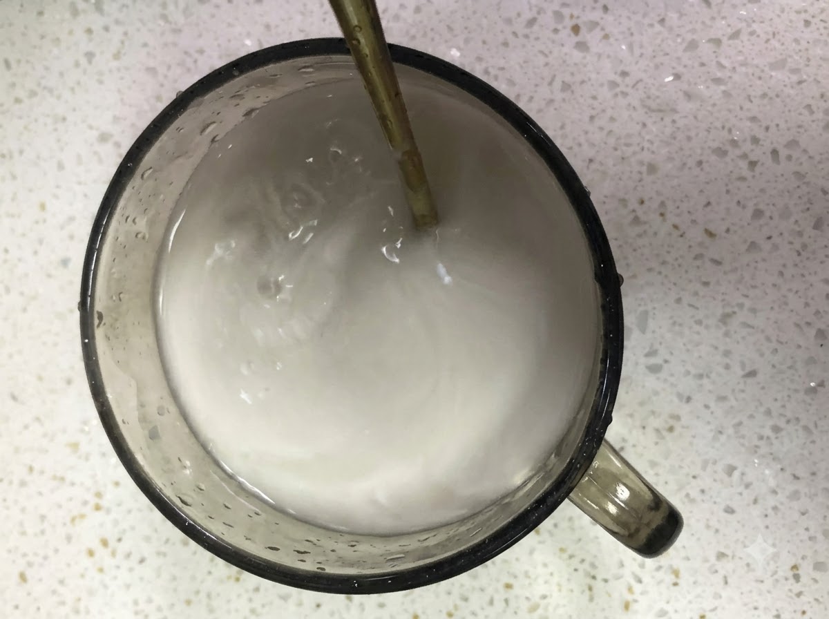 Farina di patate dolci e acqua mescolate insieme in un bicchiere di vetro con un cucchiaio.
