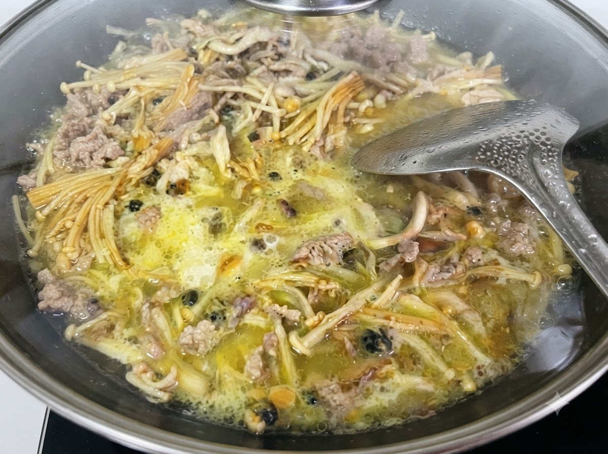 Miscela liquida di fecola di patate dolci versata da un misurino di vetro nel wok.
