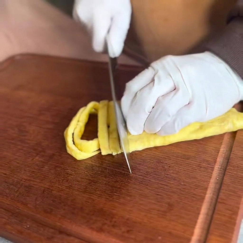 La frittata cotta tagliata a strisce sottili su un tagliere di legno.
