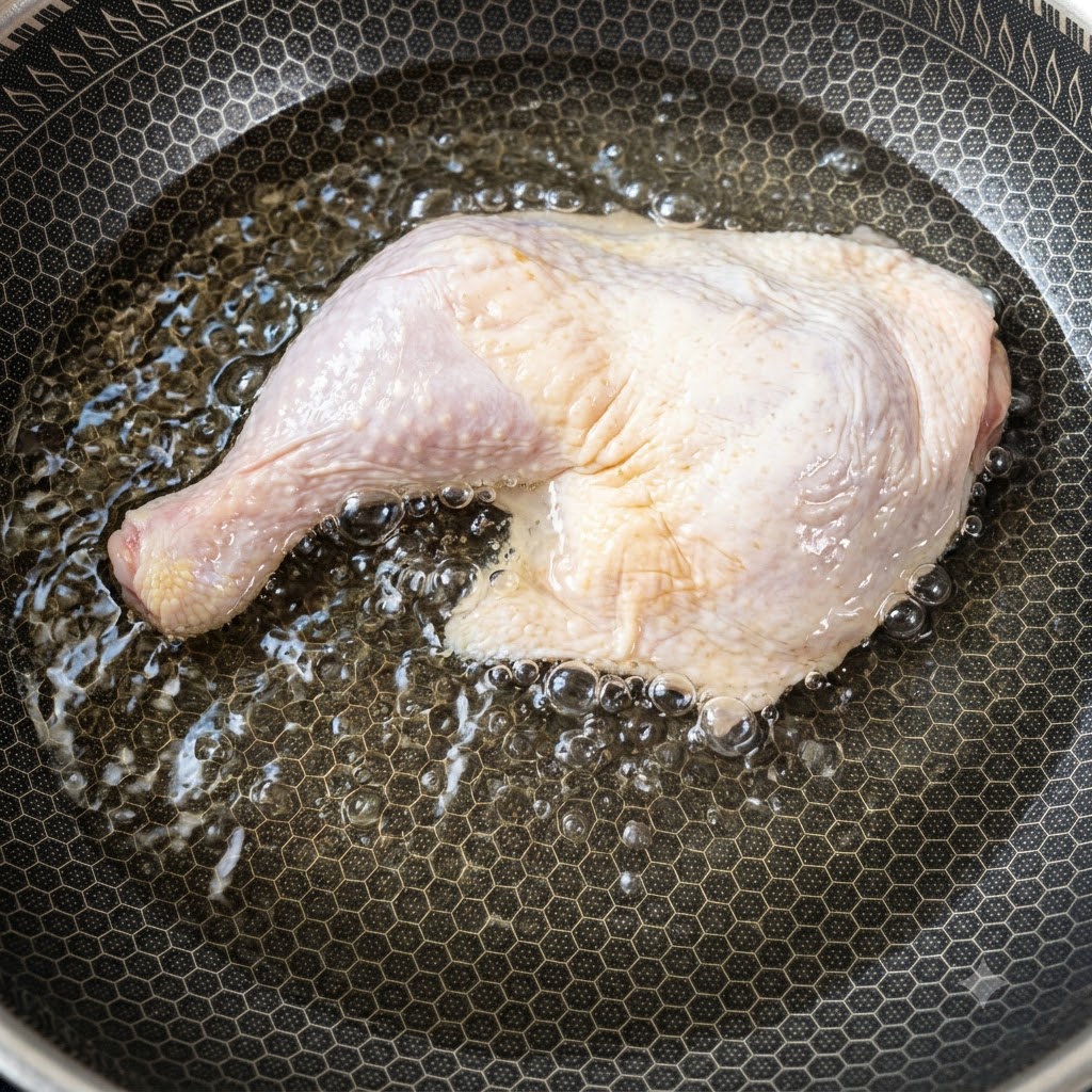 Una grande sovracoscia di pollo cruda posizionata allinterno di una padella piena di acqua fredda che inizia a scaldarsi.
