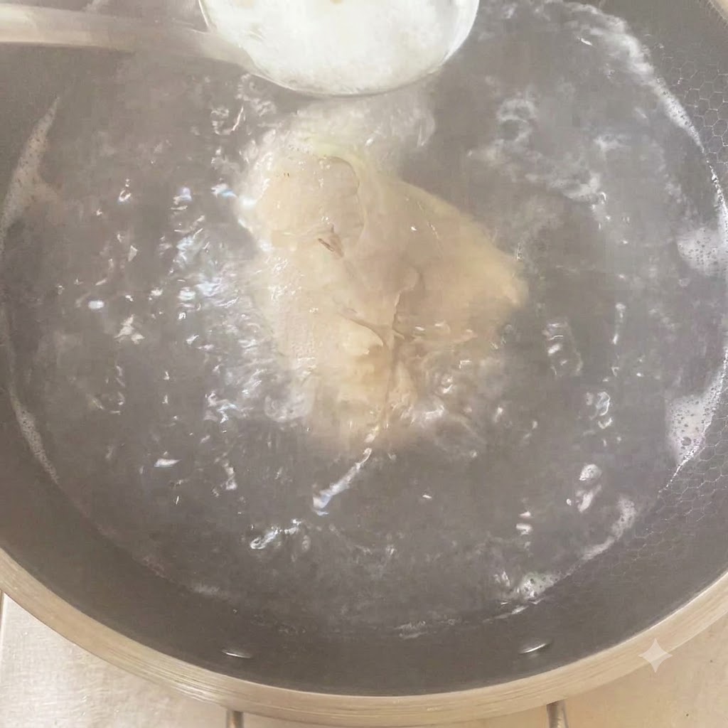 Un cucchiaio di condimento aggiunto in una pentola bollente contenente il pollo e gli aromi.