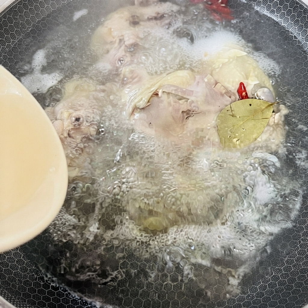 Una pentola piena di brodo di pollo bollente, spezie e una foglia di alloro che sobbolle sul fuoco.