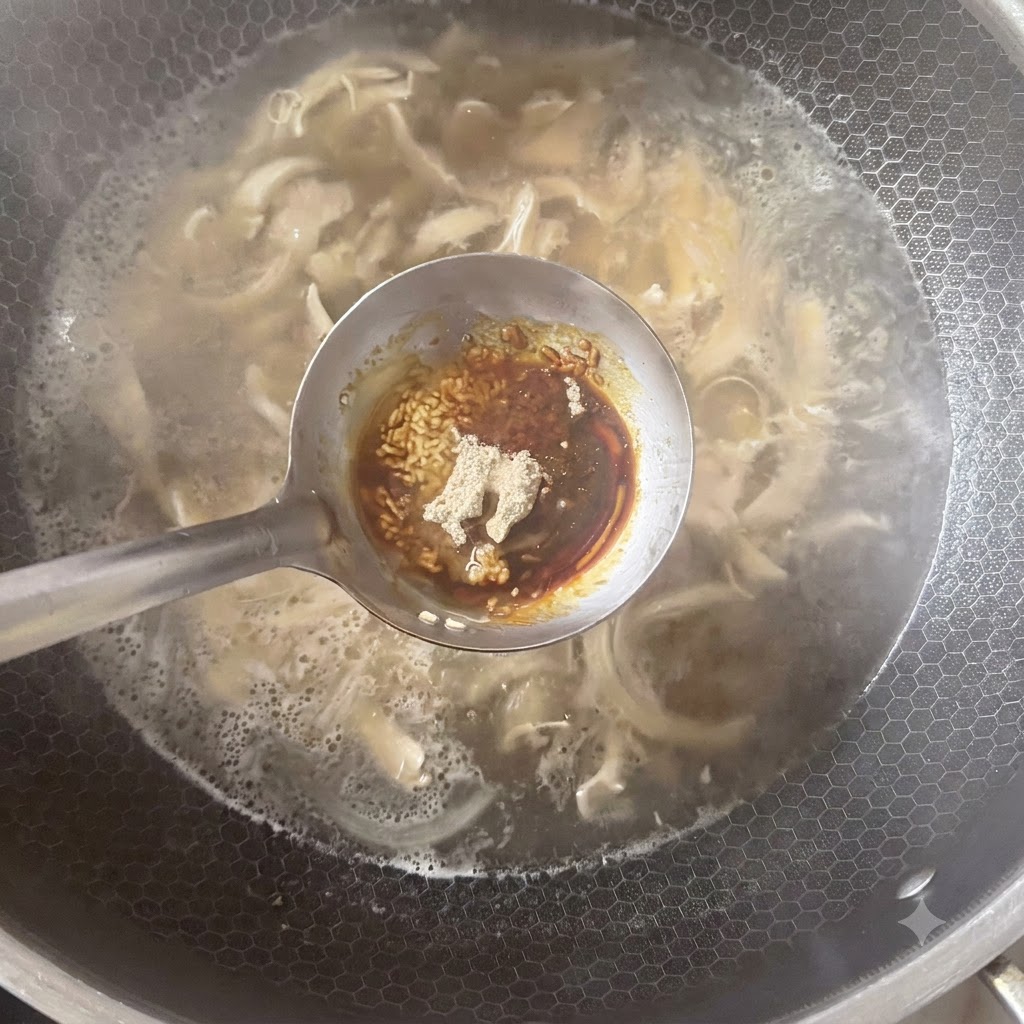 Un mestolo che contiene vari condimenti, tra cui pepe bianco in polvere e salse, posizionato sopra una pentola di zuppa in ebollizione.