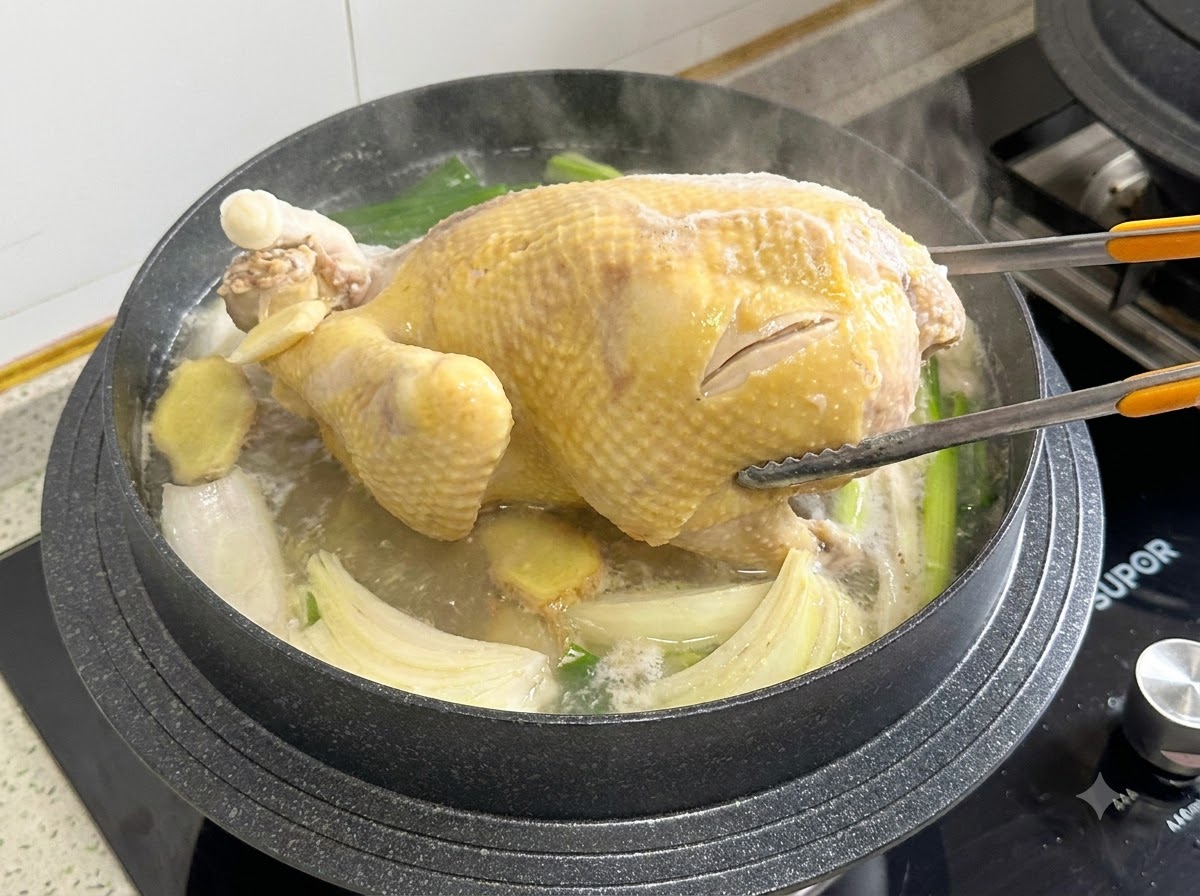 Le pinze da cucina afferrano e girano un pollo intero allinterno di una pentola di brodo bollente.