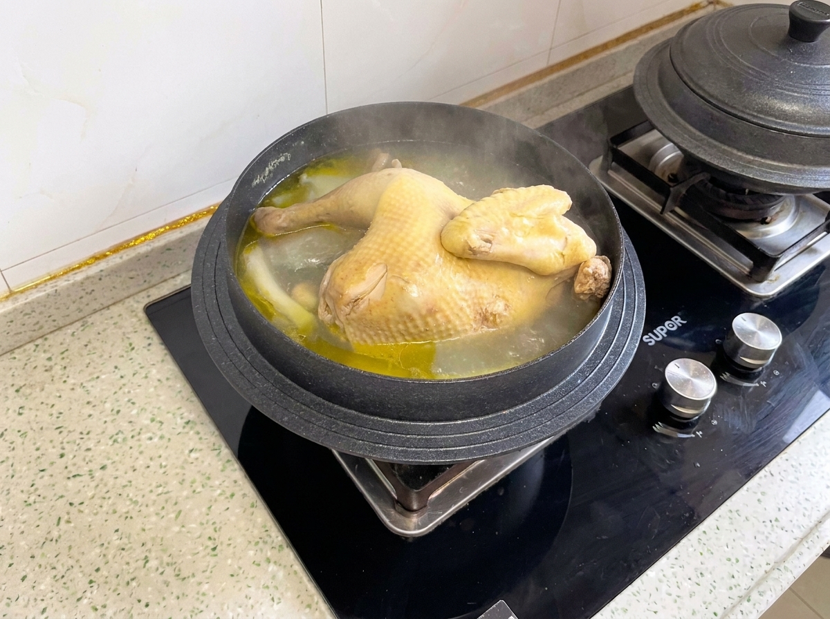 Un pollo intero cotto che sobbolle allinterno di una pentola prima di essere tagliato a pezzi.