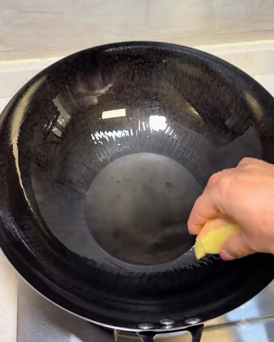 Fette di zenzero che friggono in olio caldo in un wok scuro.