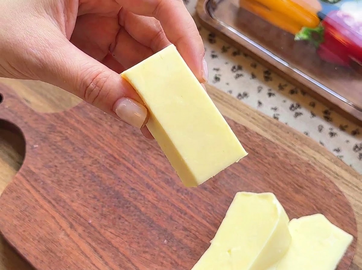 Primo piano di una mano che tiene un blocco rettangolare di mozzarella preparato per il ripieno.