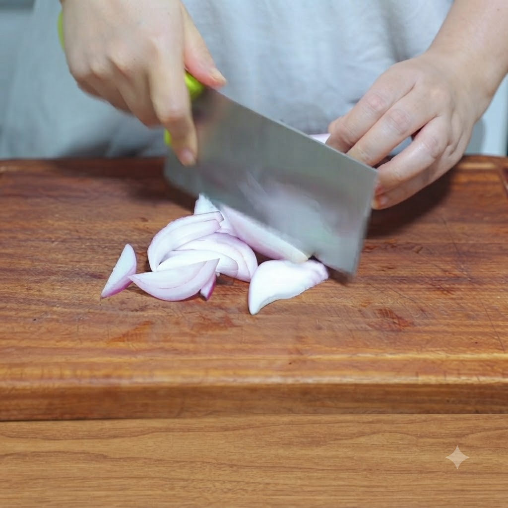 Un coltello da cucina che affetta una cipolla in strisce sottili su un tagliere di legno.