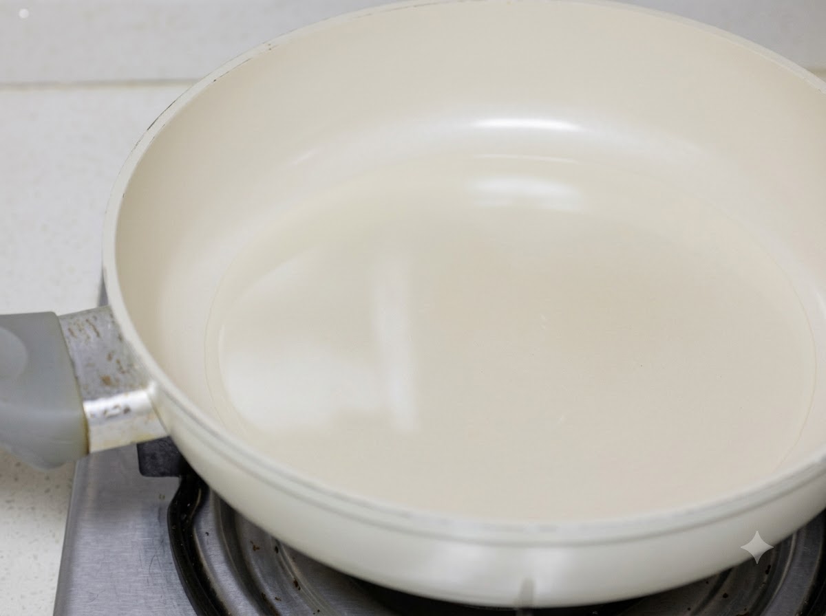 Pezzi di pollo saltati in padella con olio da cucina dentro una padella bianca.