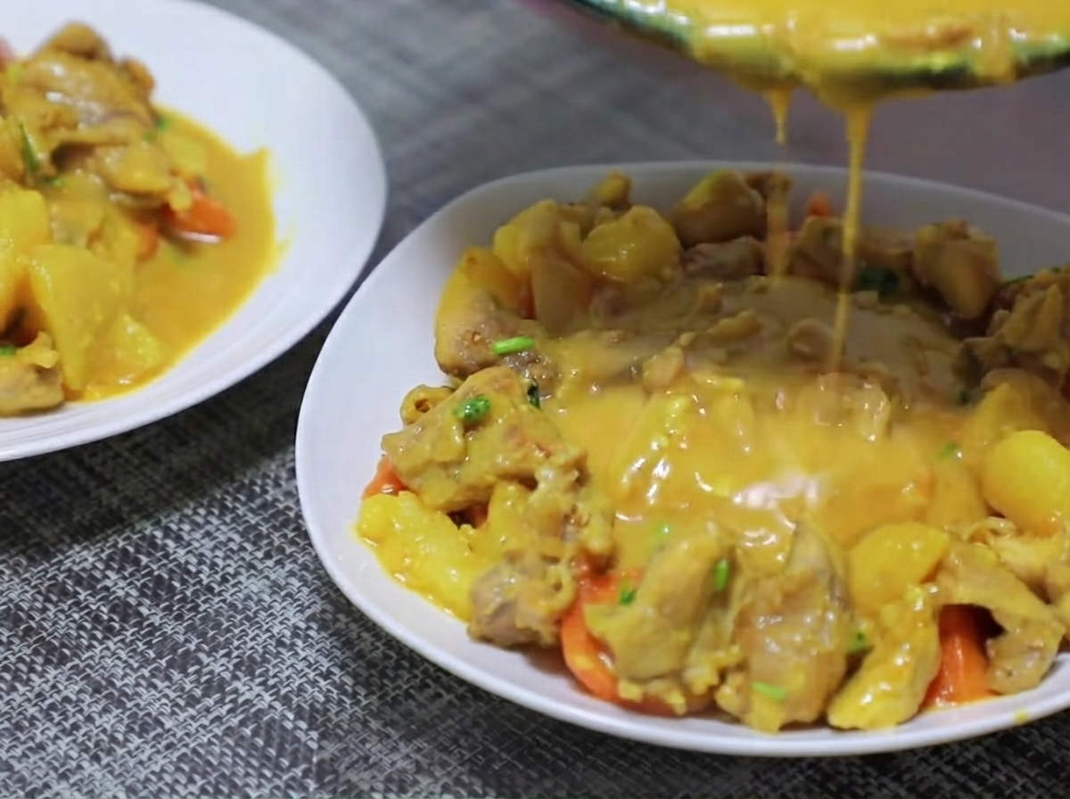 Pezzi di patate e carote aggiunti nella padella e saltati con la base di curry.