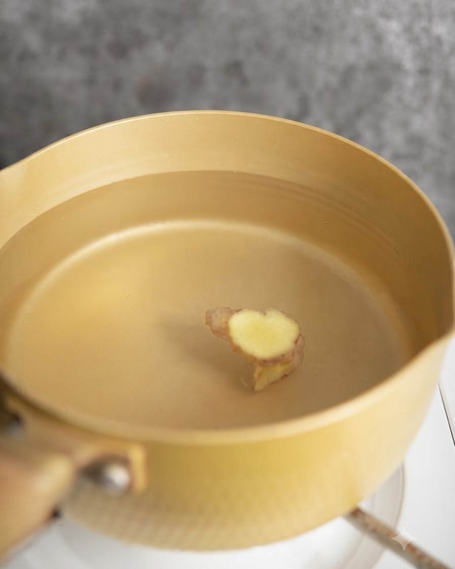 Pezzi di pollo sbollentati in una pentola dacqua con fette di zenzero.