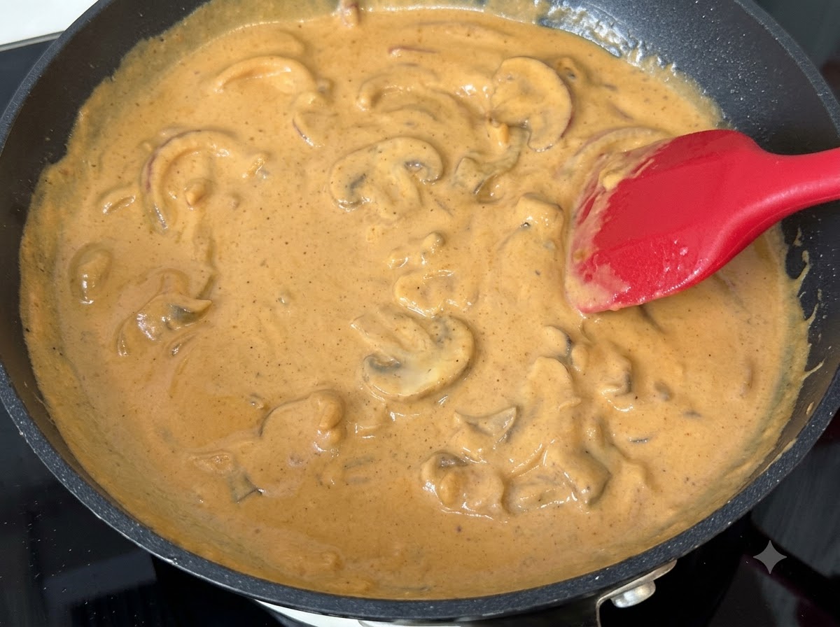 Fette di funghi mescolate nella salsa cremosa al curry in ebollizione in una padella.
