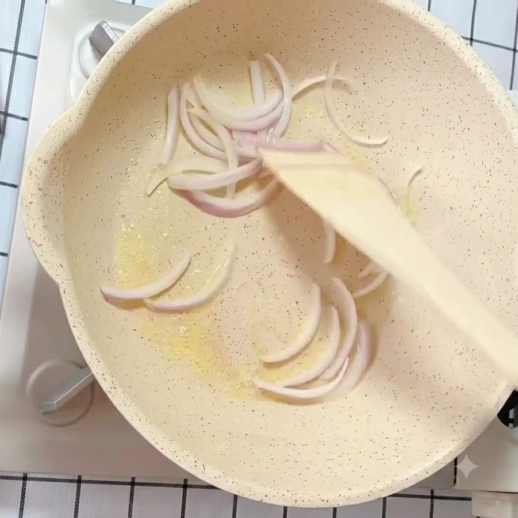 Strisce di cipolla bianca e viola saltate in padella con burro usando una spatola di legno.