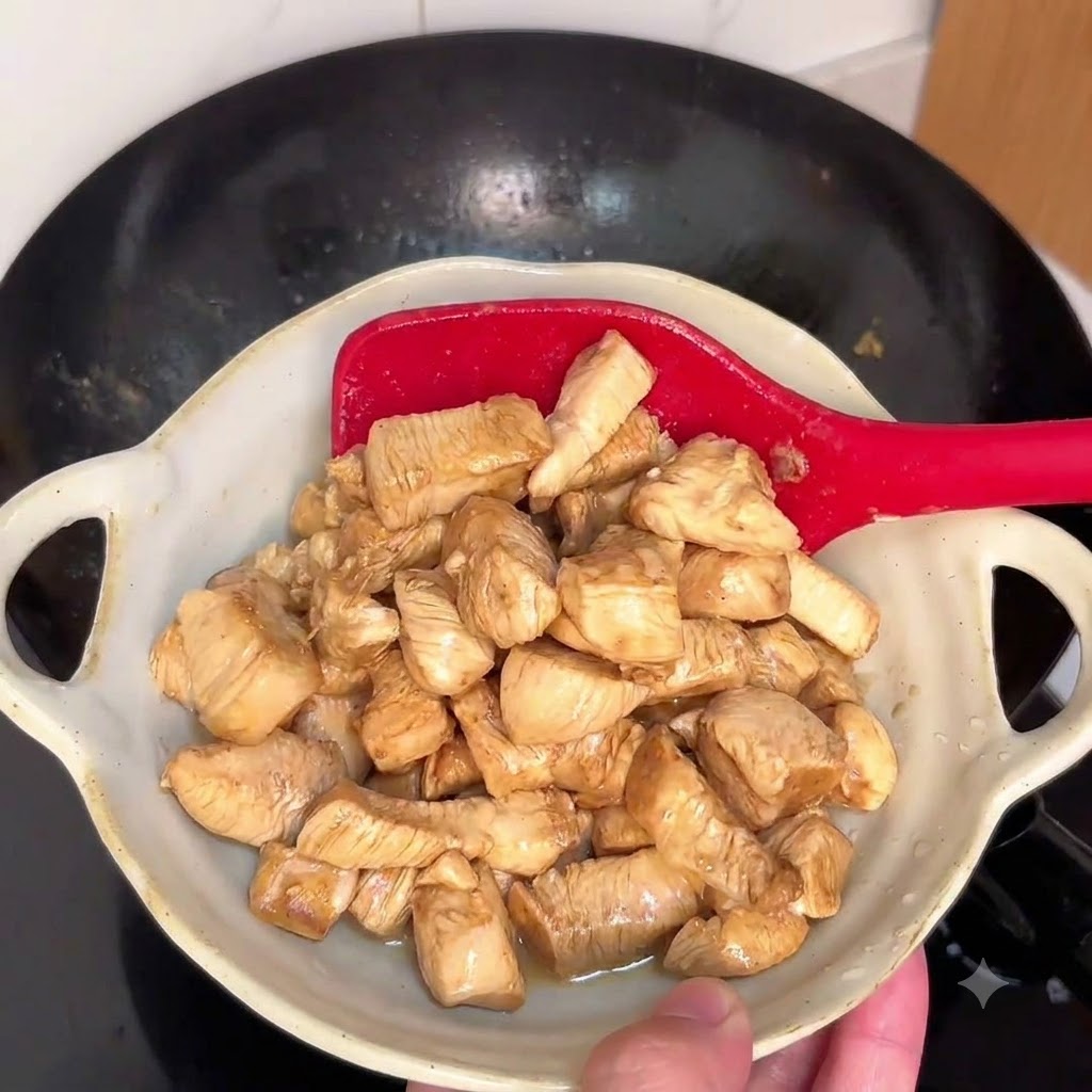Pezzi di pollo saltati in un wok caldo con una spatola rossa.
