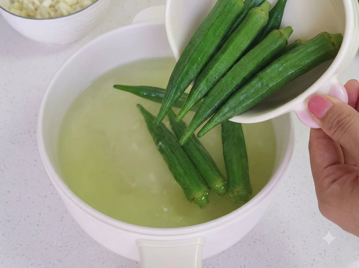 Okra cotta tagliata in piccoli segmenti su un tagliere di legno.