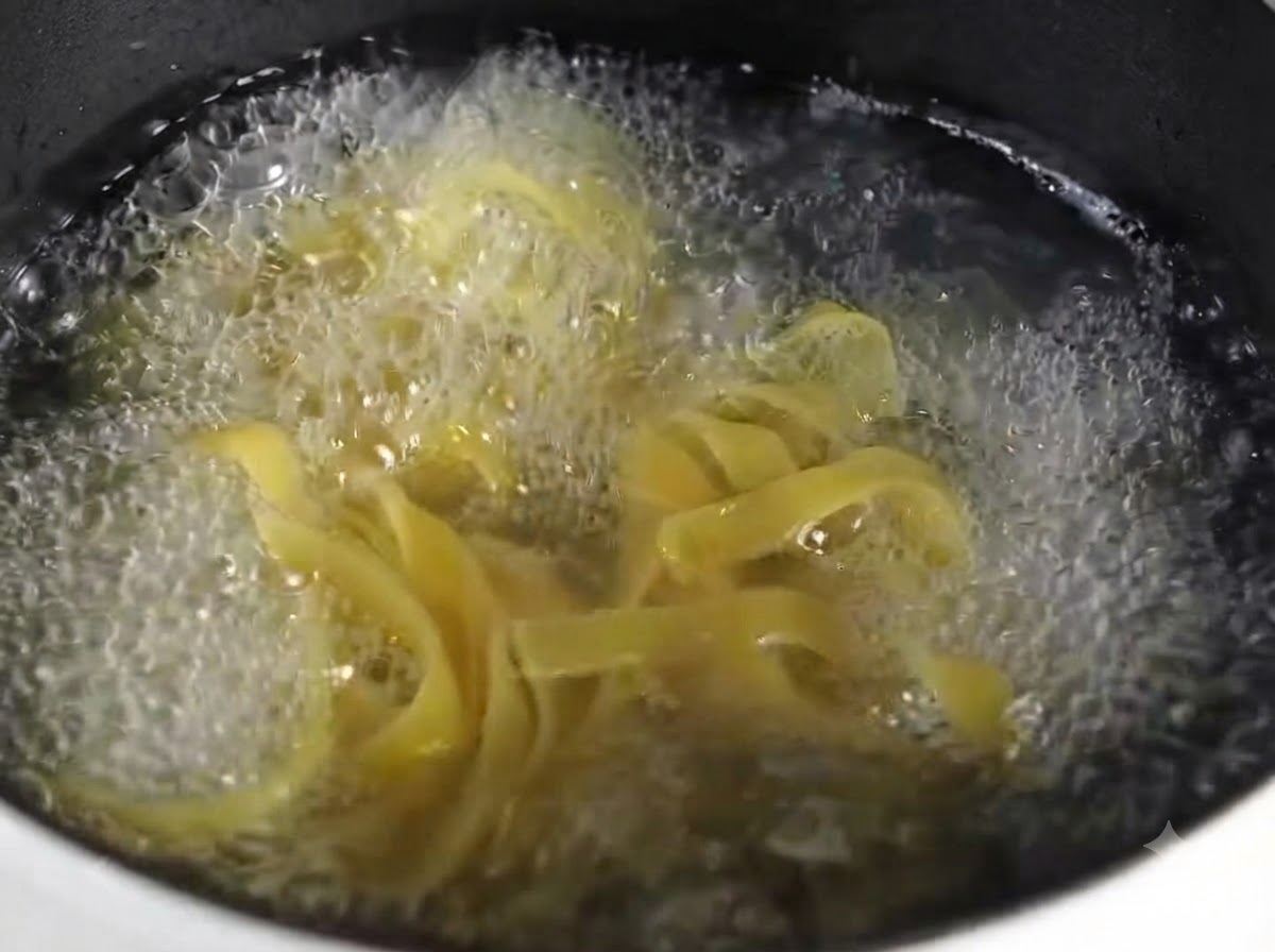 Una vista ravvicinata di pasta fettuccine cotta e disposta ordinatamente su un piatto rotondo grigio.