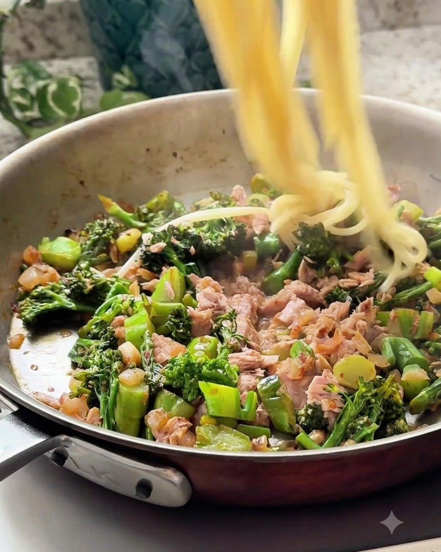 Spaghetti cotti trasferiti nella padella con il composto di tonno e verdure.