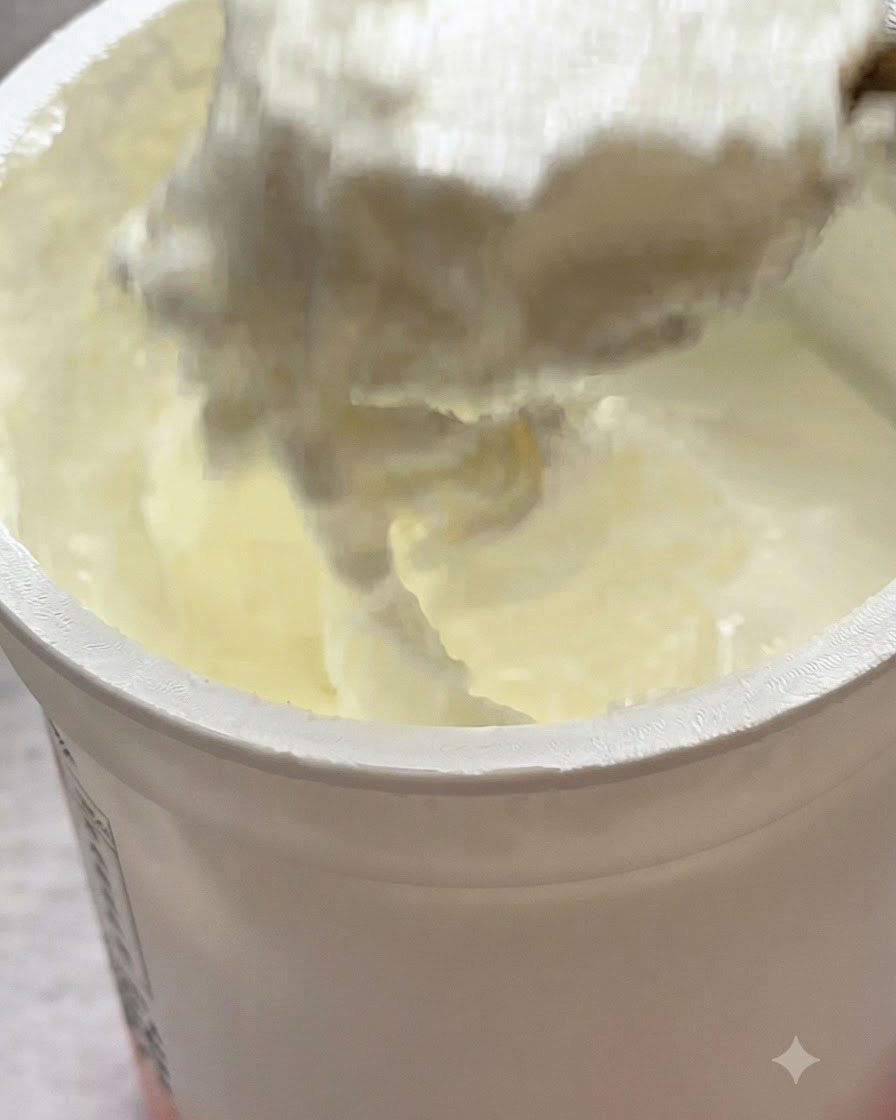 Un cucchiaio di yogurt bianco aggiunto sopra la pasta in padella.