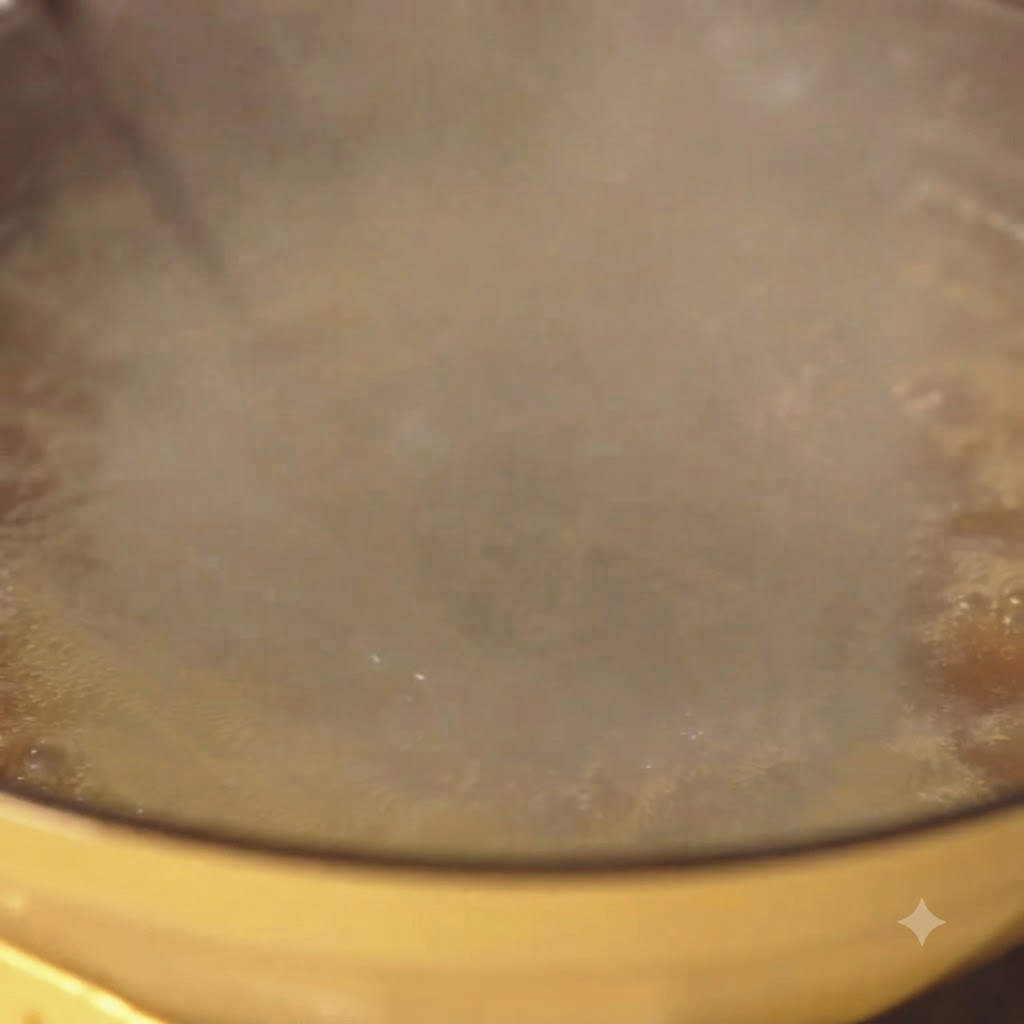 Spaghetti che bollono vigorosamente in una pentola gialla dacqua con vapore che sale.