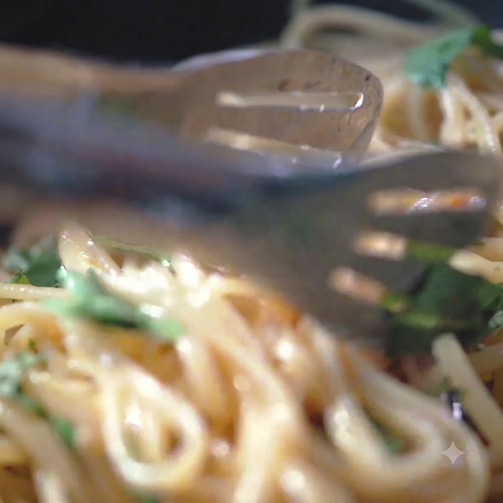Pepe nero e sale marino sparsi sui fili di pasta in una padella calda.