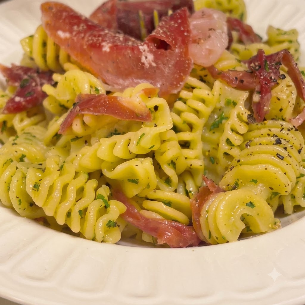 Pasta a spirale cotta mescolata in una ciotola bianca con una ricca salsa al burro usando delle pinze da cucina.