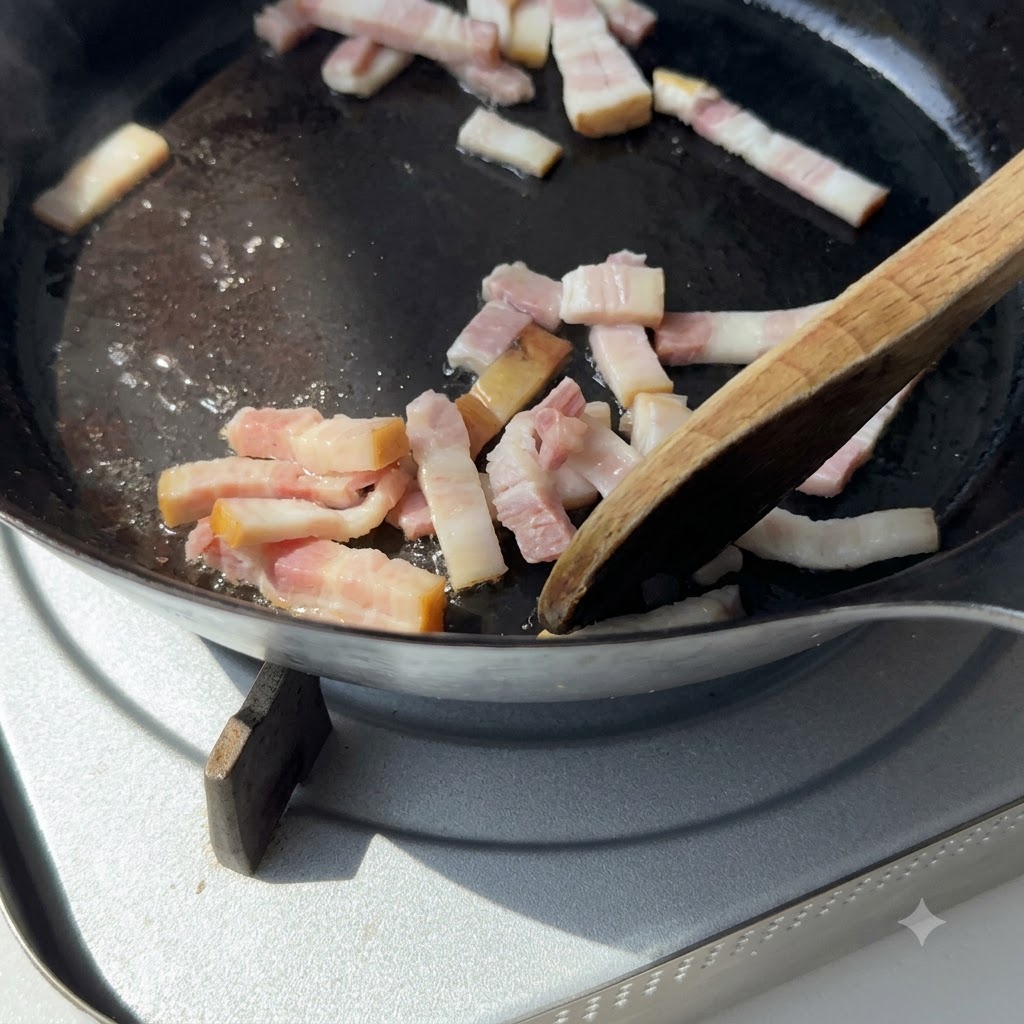 Una spatola di legno che mescola pezzi di pancetta in una padella di ghisa su un piano cottura.