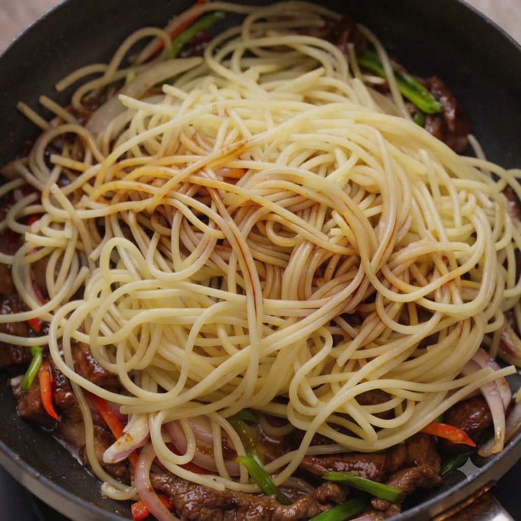 Salse gocciolate su spaghetti e manzo allinterno di una padella.