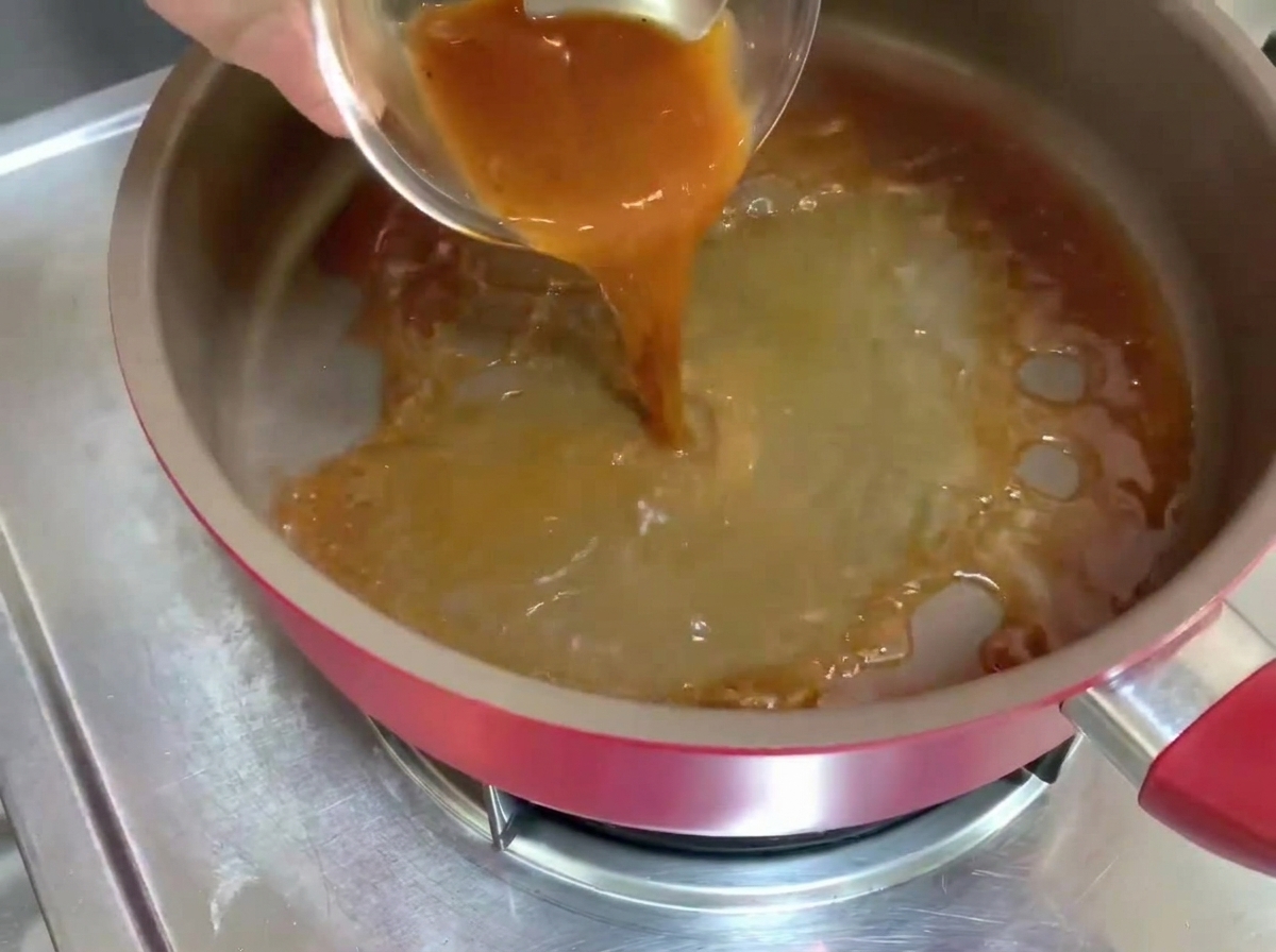 Salsa al pepe nero versata in una padella calda, che crea un liquido che bolle.