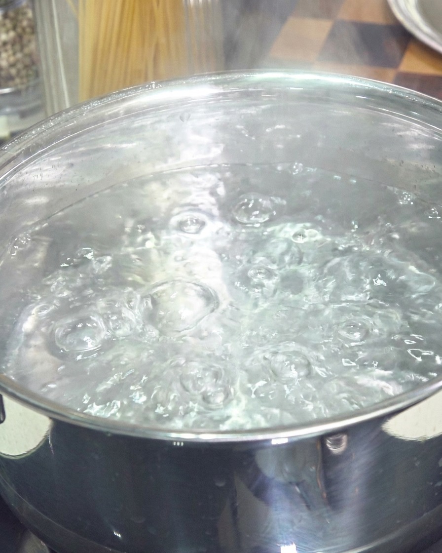 Una pentola in acciaio inossidabile piena dacqua che bolle vivacemente.