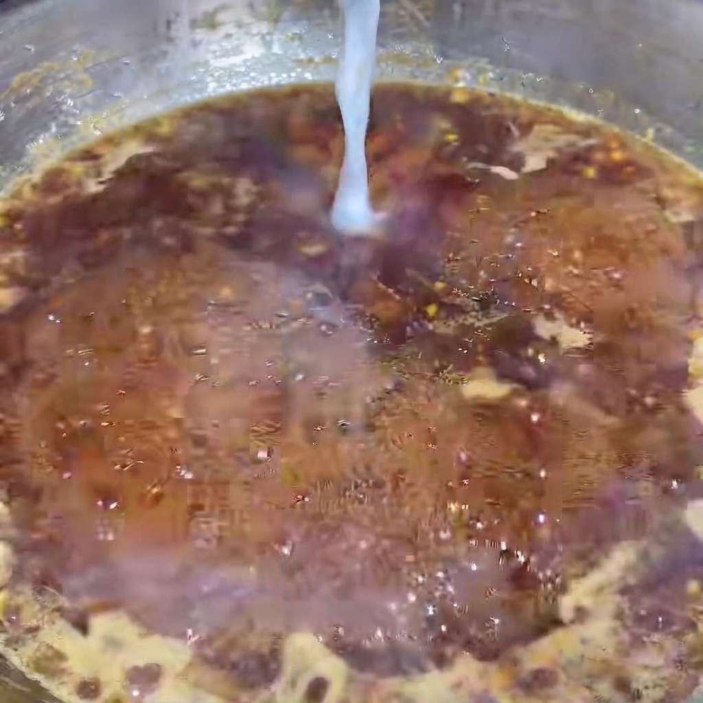 Un sottile filo di acqua e amido bianco versato in una salsa al pepe nero scura e spumeggiante in una padella calda.