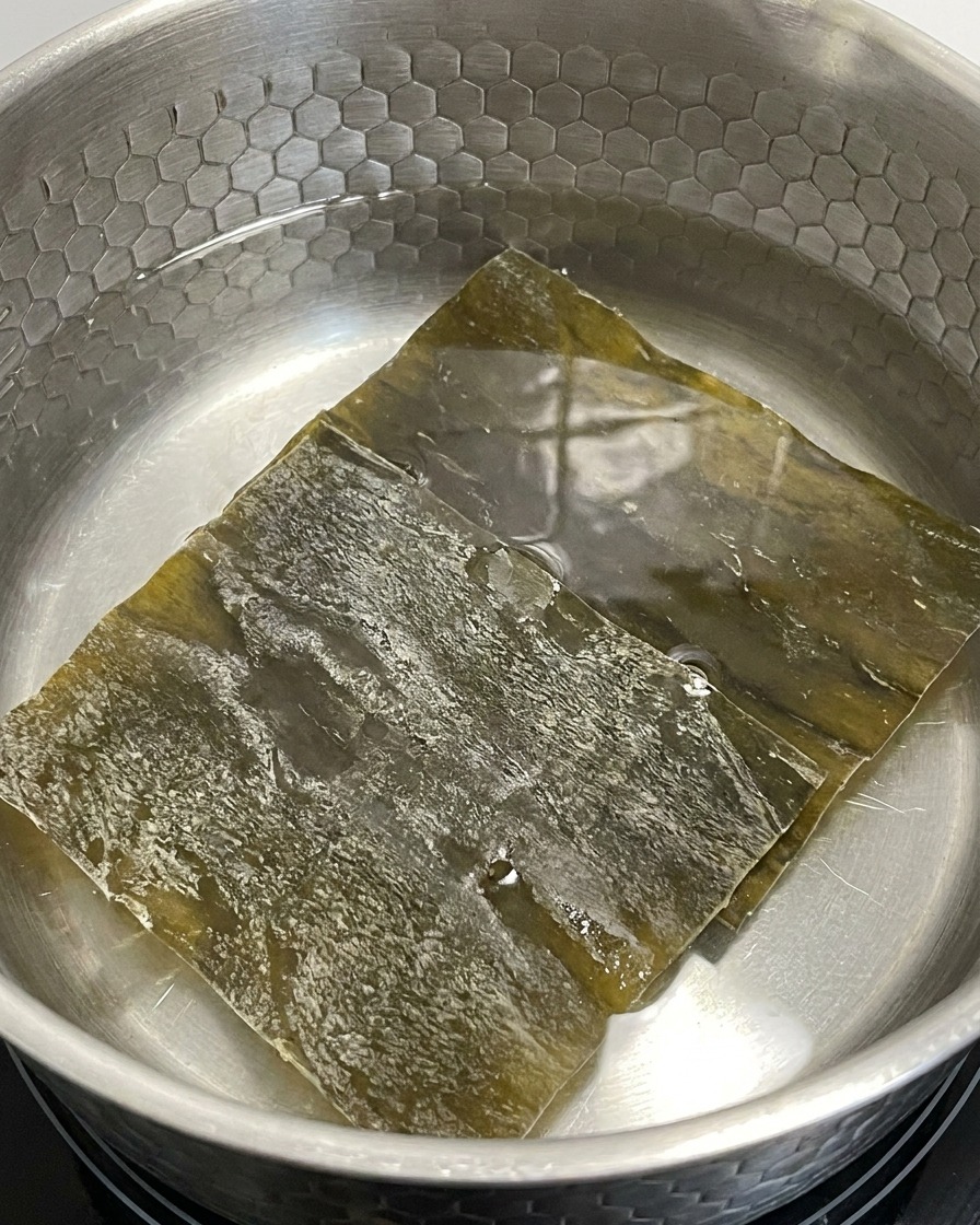 Pezzi di alga kelp in infusione in una pentola dacqua a fuoco basso.